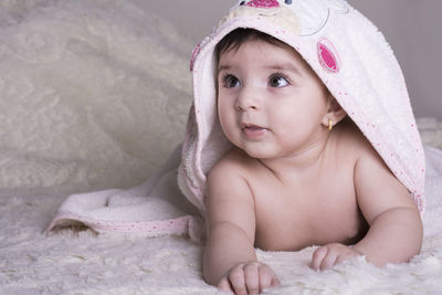 Portrait of cute baby girl lying on bed