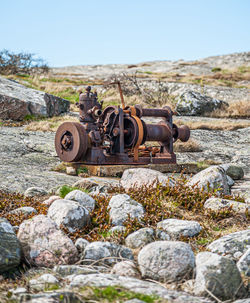 Close-up of old rusty wheel on rock against sky