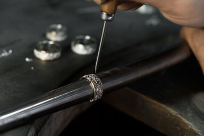 Close-up of hand of a goldsmith setting the diamond on the ring. craft jewelery, professional tools.