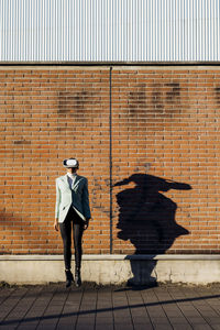 Businesswoman with vr goggles jumping in front of wall