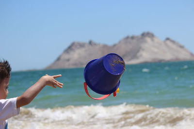 People at beach against clear blue sky