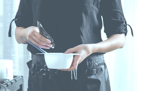 Midsection of woman pouring hair dye in bowl