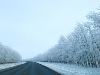 Road amidst snow covered trees against sky