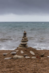 Stack of stones on beach against sky