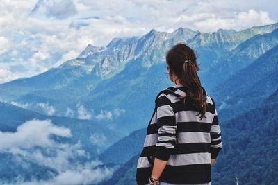 Rear view of woman standing on mountain against sky