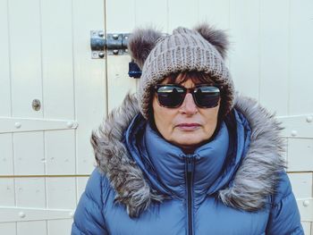 Woman wearing sunglasses standing against closed door