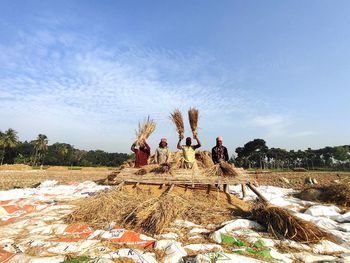 Group of people on wooden logs on land against sky