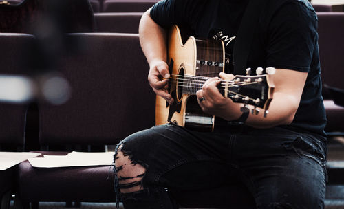 Midsection of man playing guitar