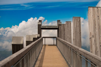 Wooden footbridge over sea against sky