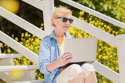 Senior authentic woman using laptop for distance learning education outdoors