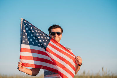 Low angle view of man flag against clear blue sky