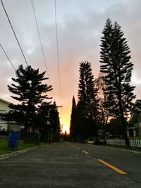 Road amidst trees against sky during sunset