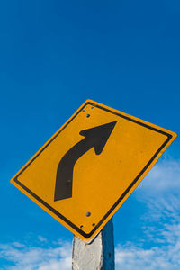 Low angle view of road sign against blue sky