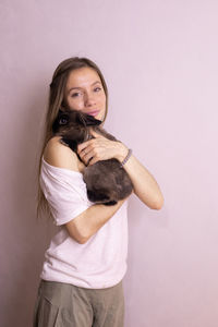 Portrait of smiling young woman with dog against white background