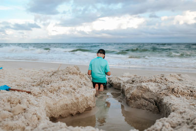 Rear view of woman on beach against sky