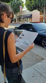 Woman standing by car on street in city