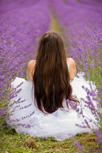 Rear view of girl with flowers on field