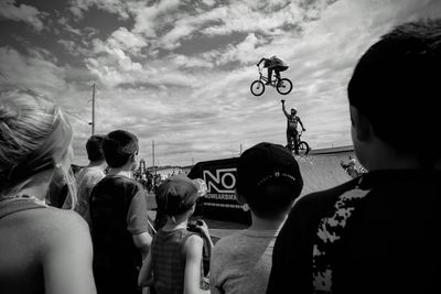 Rear view of people enjoying on motorcycle against sky