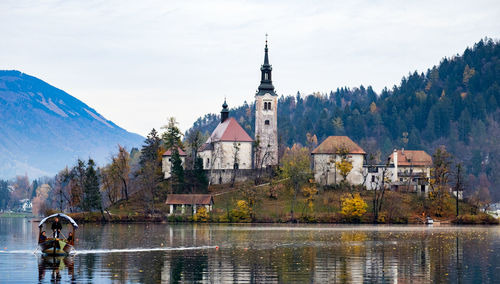 People on boat sailing in lake bled against church