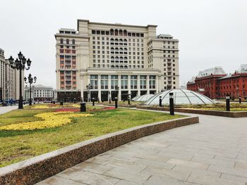 Footpath by buildings against sky in city