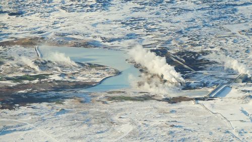 High angle view of smoke erupting from volcanic landscape