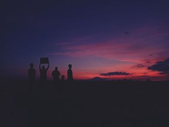 Silhouette people on landscape against sky during sunset