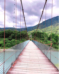 Footbridge over mountain against sky