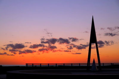 Silhouette bridge over sea against sky during sunset