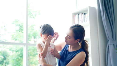 Young woman standing against window