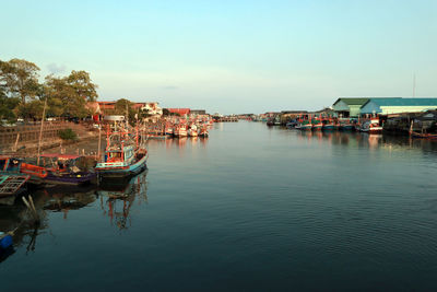 Boats moored in marina by buildings against sky