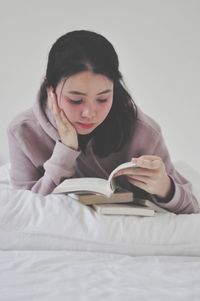 Young woman looking away while sitting on bed at home