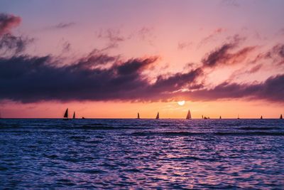 Silhouette sailboat sailing on sea against dramatic sky during sunset