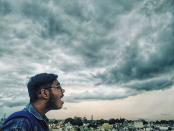 Side view of young man in city against sky