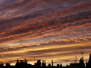 Silhouette of buildings against cloudy sky during sunset