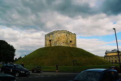 Cars on road against cloudy sky