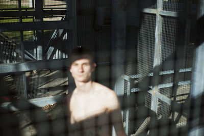 Portrait of shirtless man seen through window