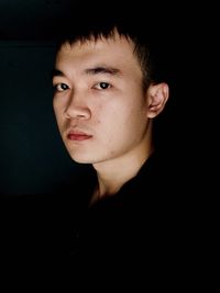 Portrait of young man against black background