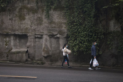 Rear view of people on road against trees in city