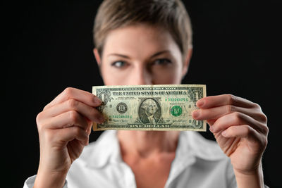 Midsection of woman holding paper currency against black background