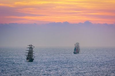 Sailboat sailing on sea against sky during sunset