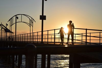 Silhouette people standing on pier against clear sky during sunset