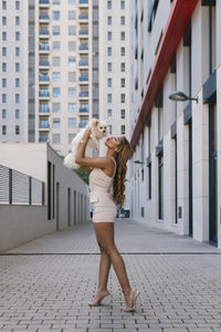 Full length of woman standing on footpath against building