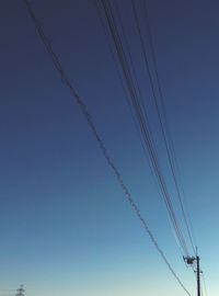 Low angle view of power lines against clear blue sky