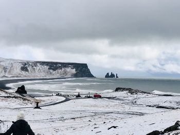 Scenic view of sea by snowcapped mountains against sky