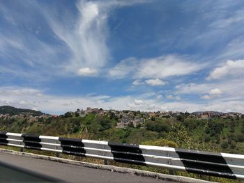 Road by trees against sky in city