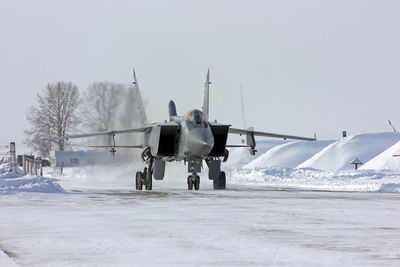 Airplane on snowy field against clear sky