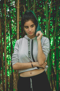 Thoughtful young woman looking away against trees in forest