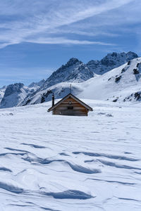 House on snowcapped mountain against sky