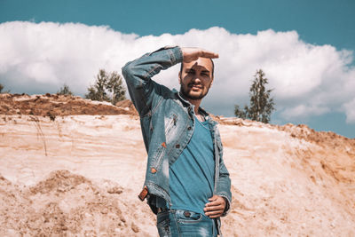 Young man wearing sunglasses standing on land against sky