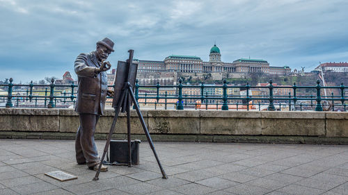 Man sculpture in city against sky